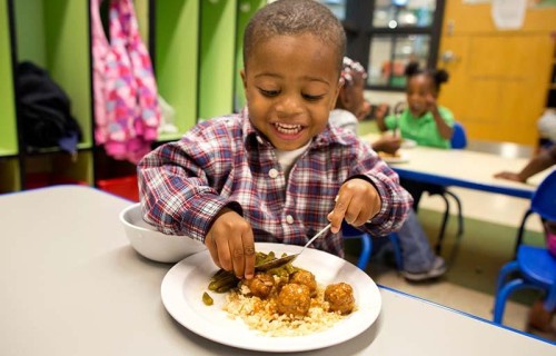 Student eating fresh meal prepared in Operation Breakthrough kitchen.