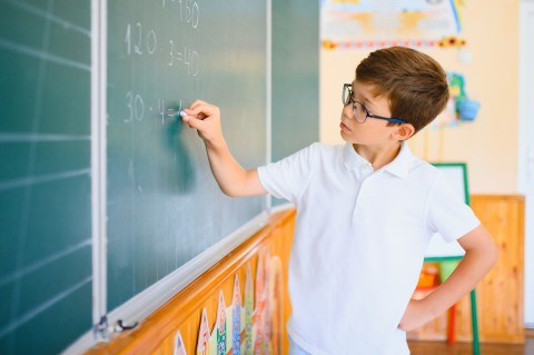 Student doing math on a chalkboard. 