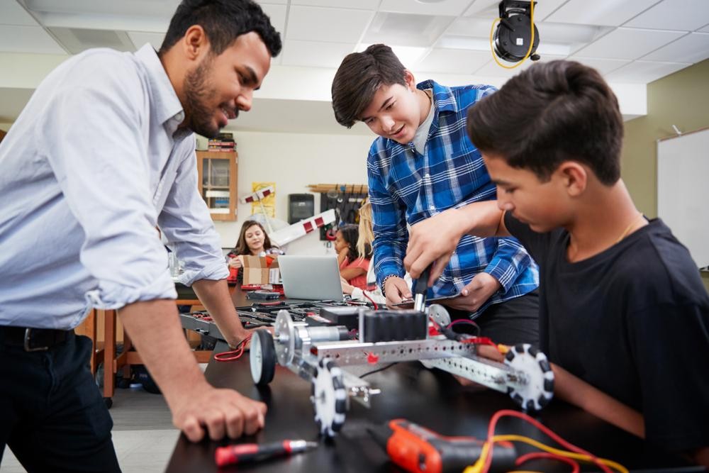 Teacher oversees students working on robotics