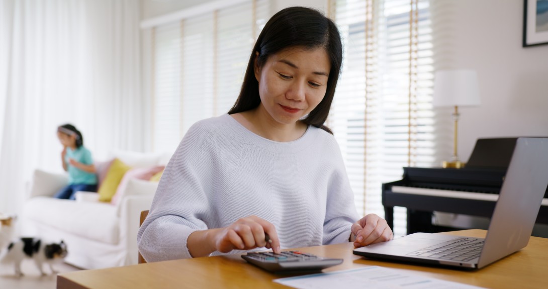 Woman calculating taxes with child in the background. 