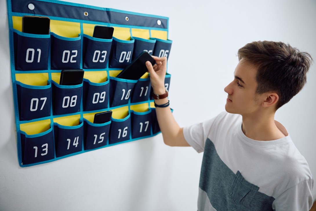 High school student leaving his smart phone in cell phone organizer